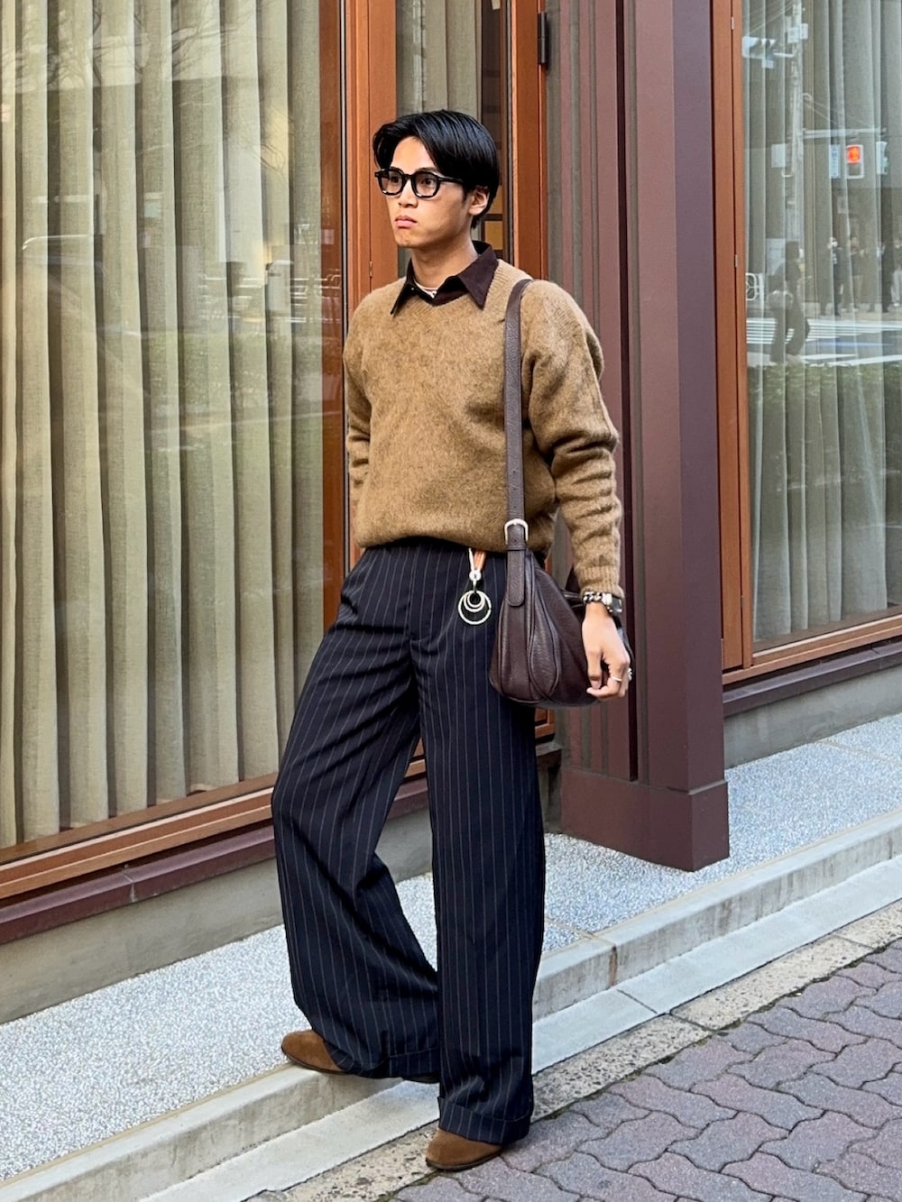 イエロー系のニット/セーター、ブラウン系のシャツ/ブラウス、ブラック系のスラックスを着用したメンズの春コーディネートの3枚目の写真