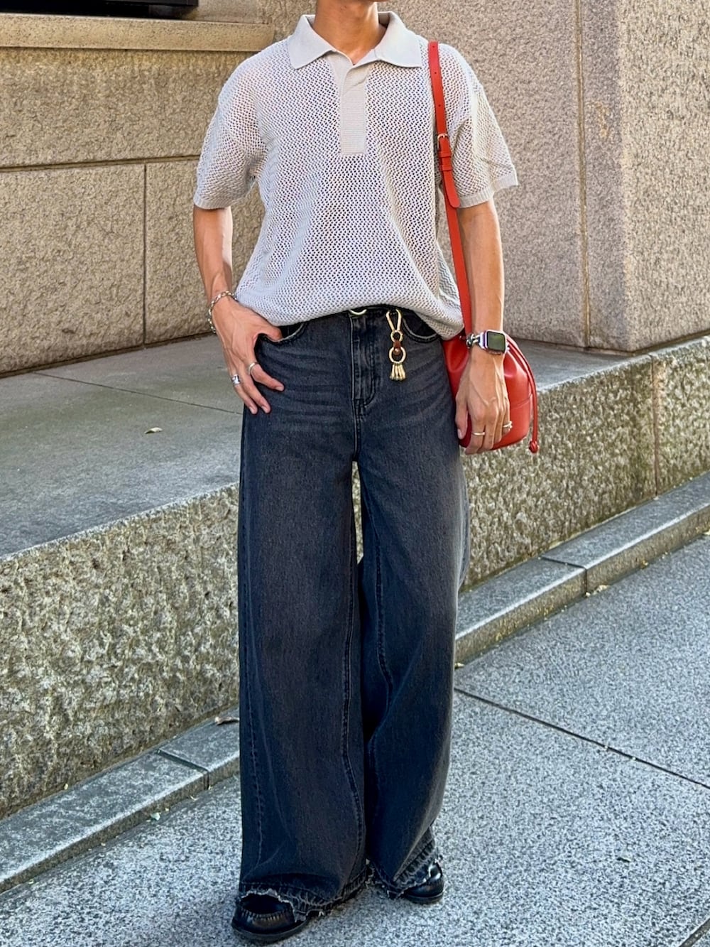 ブラック系のデニムパンツ、グレー系のポロシャツ、オレンジ系のバッグを着用したメンズの夏コーディネートの4枚目の写真