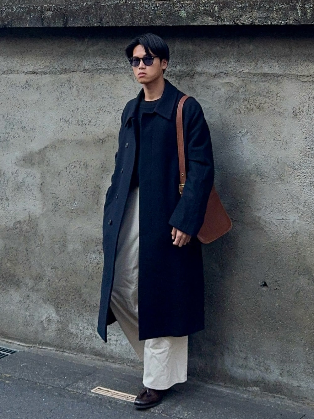 ブラック系のニット/セーター、ホワイト系のデニムパンツ、ブラウン系のローファーを着用したメンズの春コーディネートの5枚目の写真