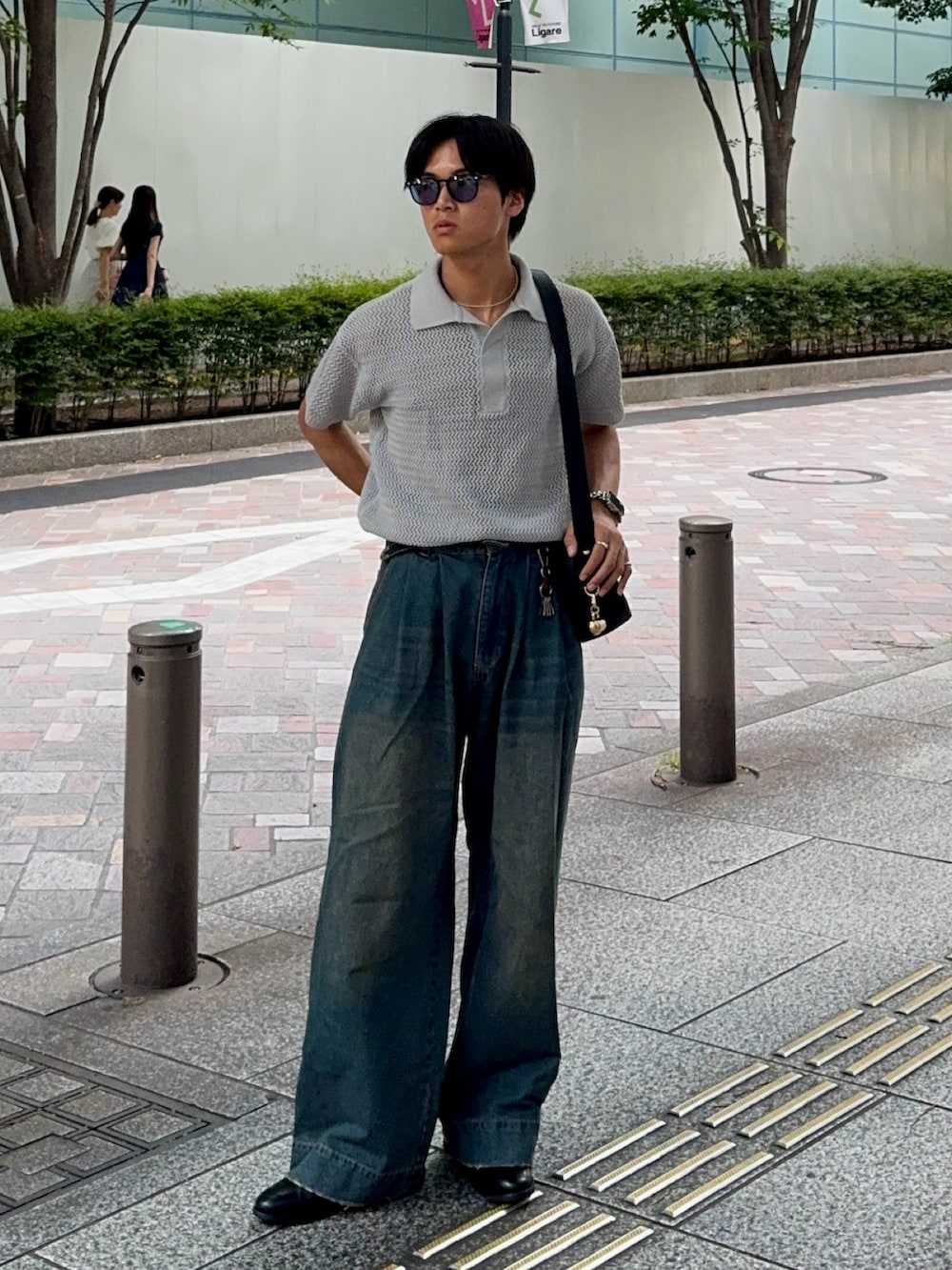 ブルー系のデニムパンツ、ブラック系のハンドバッグ、ブラック系のドレスシューズを着用したメンズの夏コーディネートの5枚目の写真