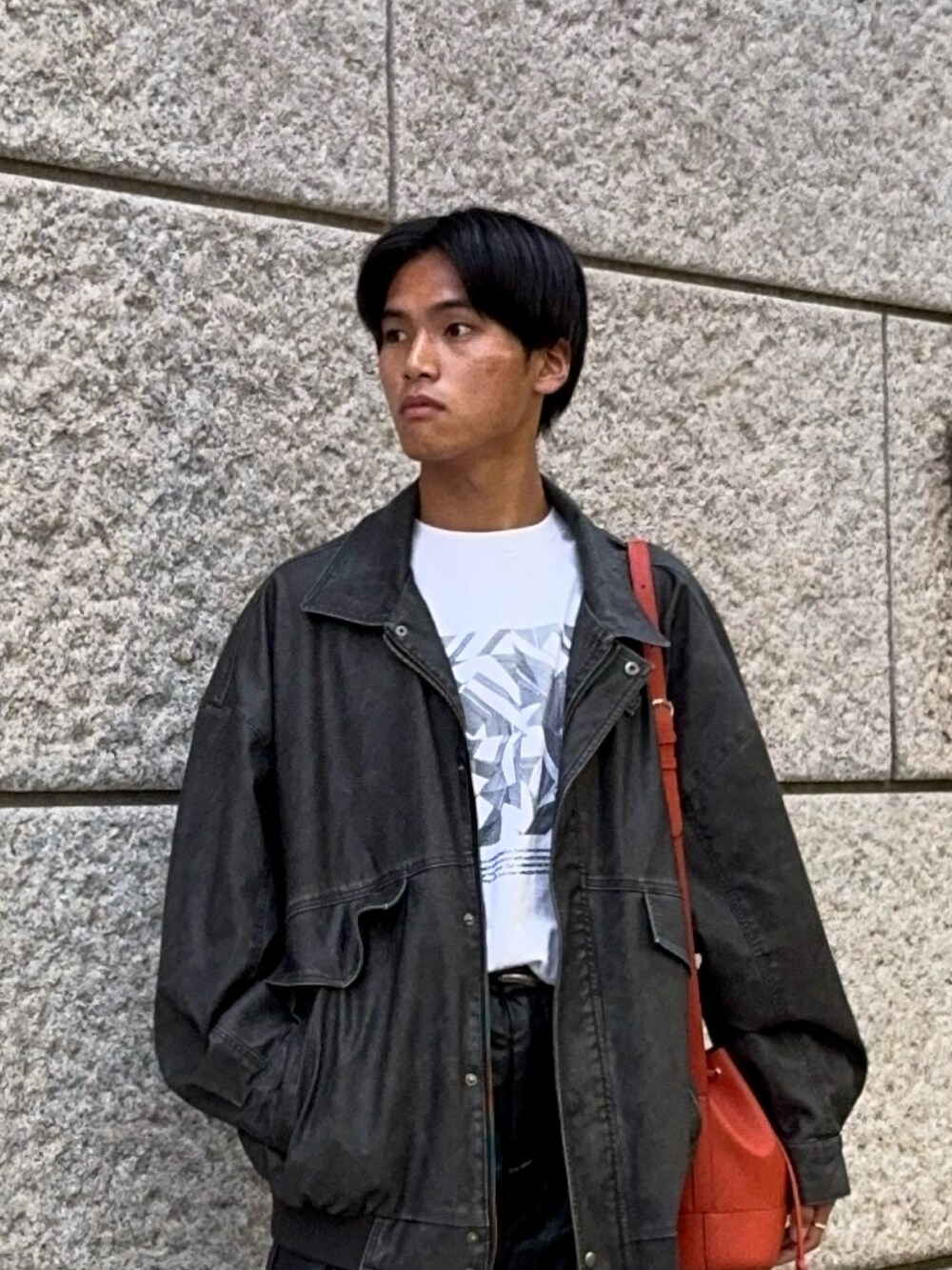 ブラック系のブルゾン、その他のTシャツ/カットソー、オレンジ系のバッグを着用したメンズの秋コーディネートの2枚目の写真