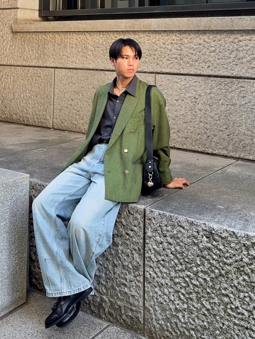 グリーン系のテーラードジャケット、ブラック系のハンドバッグ、ブラック系のローファーを着用したメンズの春コーディネートの3枚目の写真