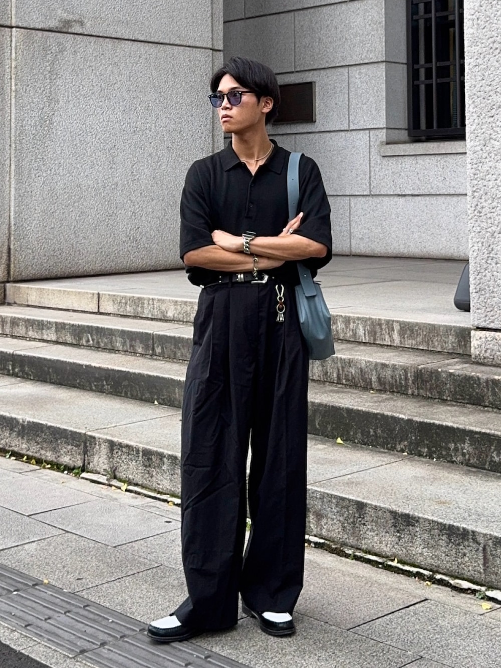 ブラック系のローファー、ブラック系のポロシャツ、ブルー系のショルダーバッグを着用したメンズの夏コーディネートの3枚目の写真