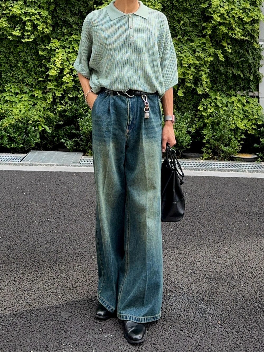 ブルー系のデニムパンツ、ブラック系のバッグ、グリーン系のポロシャツを着用したメンズの夏コーディネートの4枚目の写真