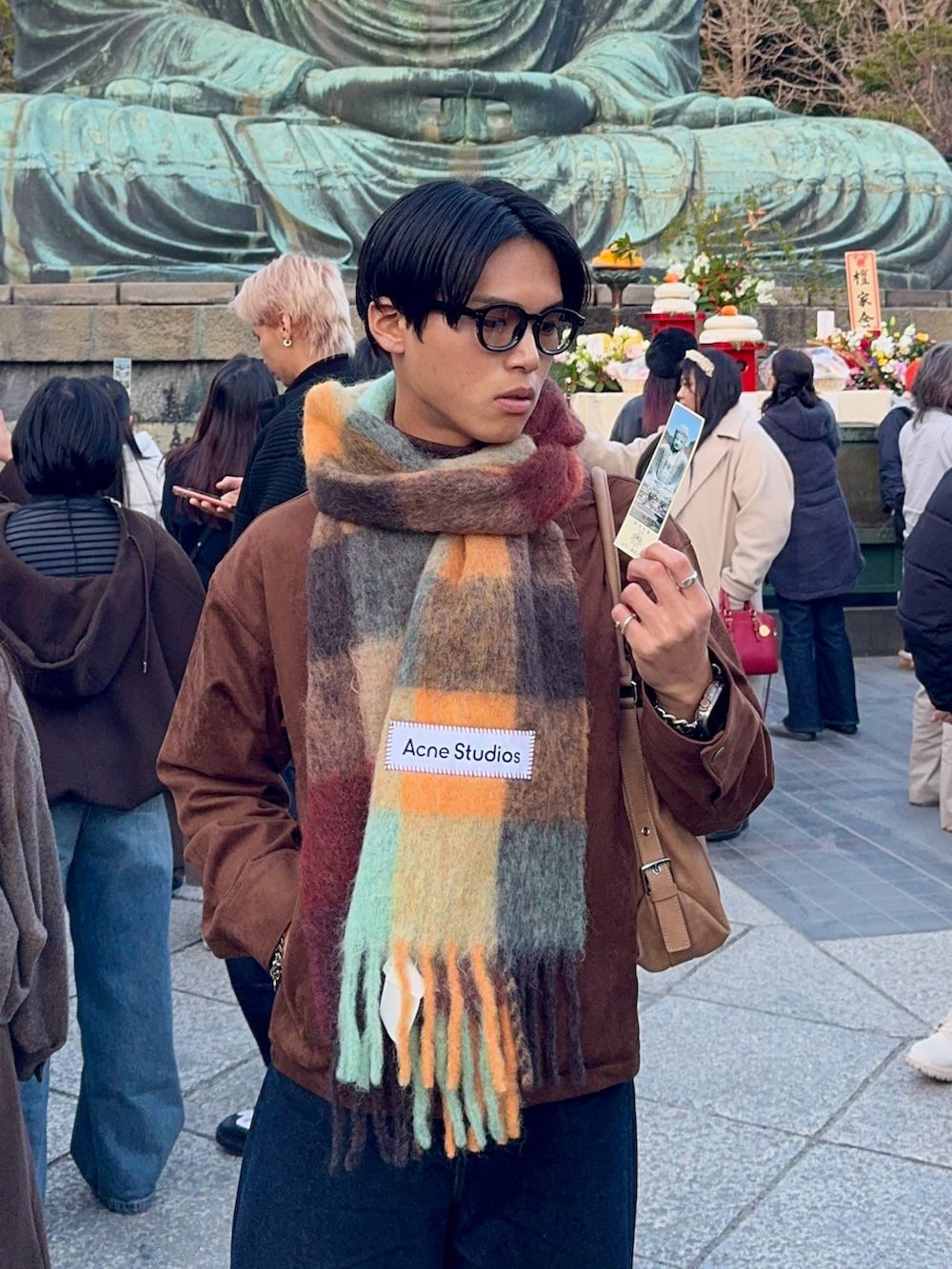 ブラウン系のブルゾン、ブルー系のデニムパンツ、ベージュ系のショルダーバッグを着用したメンズの冬コーディネートの2枚目の写真