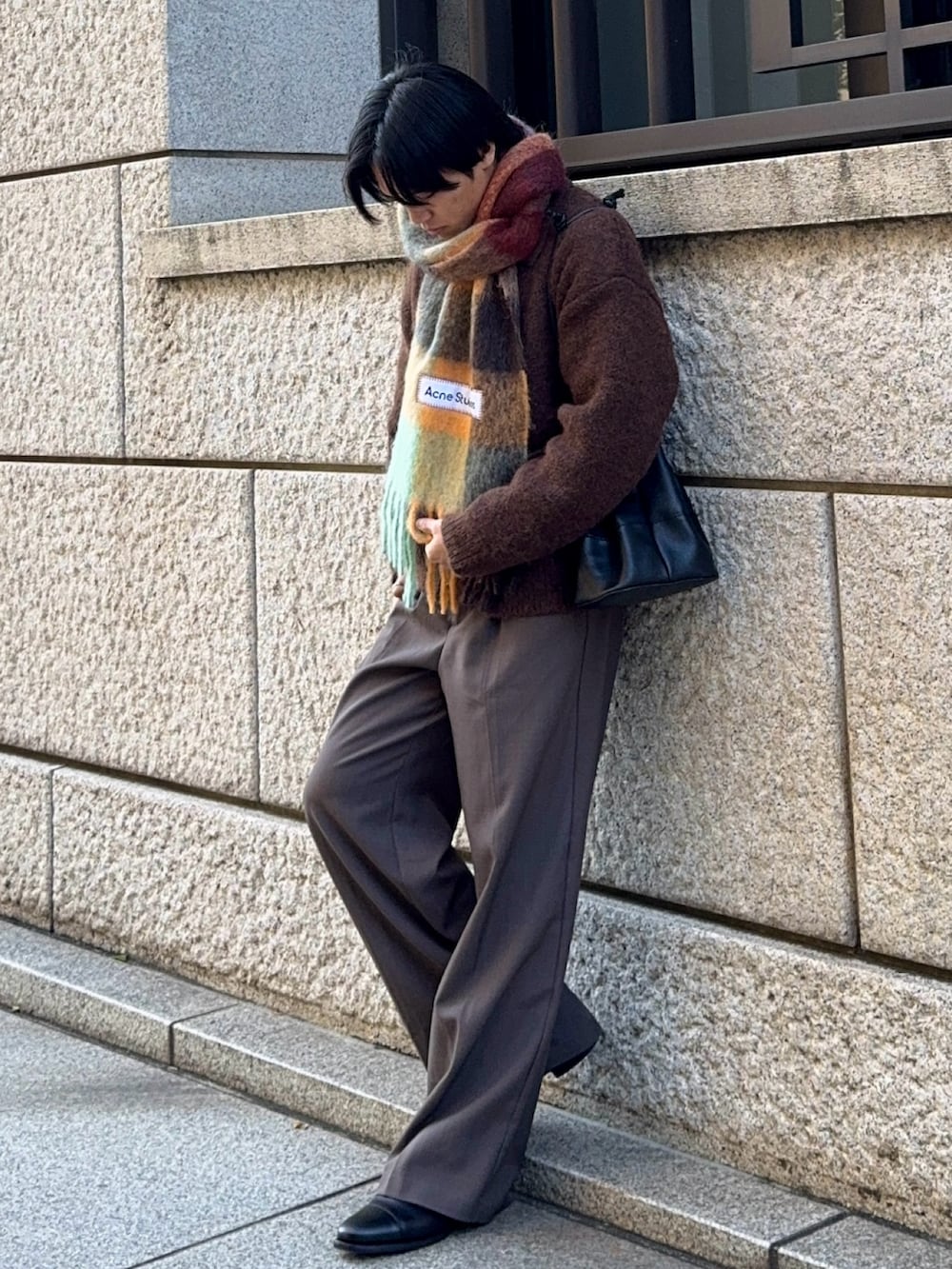 ブラウン系のスラックス、ブラック系のドレスシューズ、ブラウン系のカーディガン/ボレロを着用したメンズの冬コーディネートの3枚目の写真