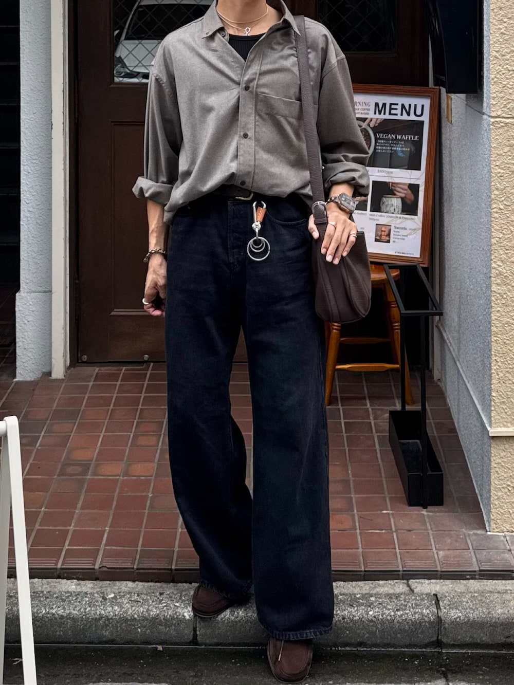 ブラック系のタンクトップ、ブラック系のデニムパンツ、ブラウン系のショルダーバッグを着用したメンズの秋コーディネートの4枚目の写真