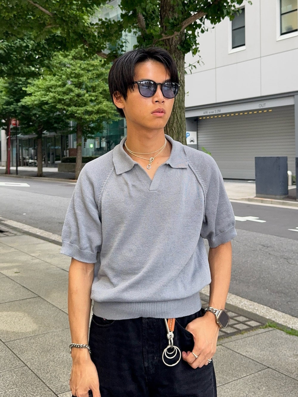 ブラック系のデニムパンツ、ブルー系のポロシャツ、ブラック系のハンドバッグを着用したメンズの夏コーディネートの2枚目の写真