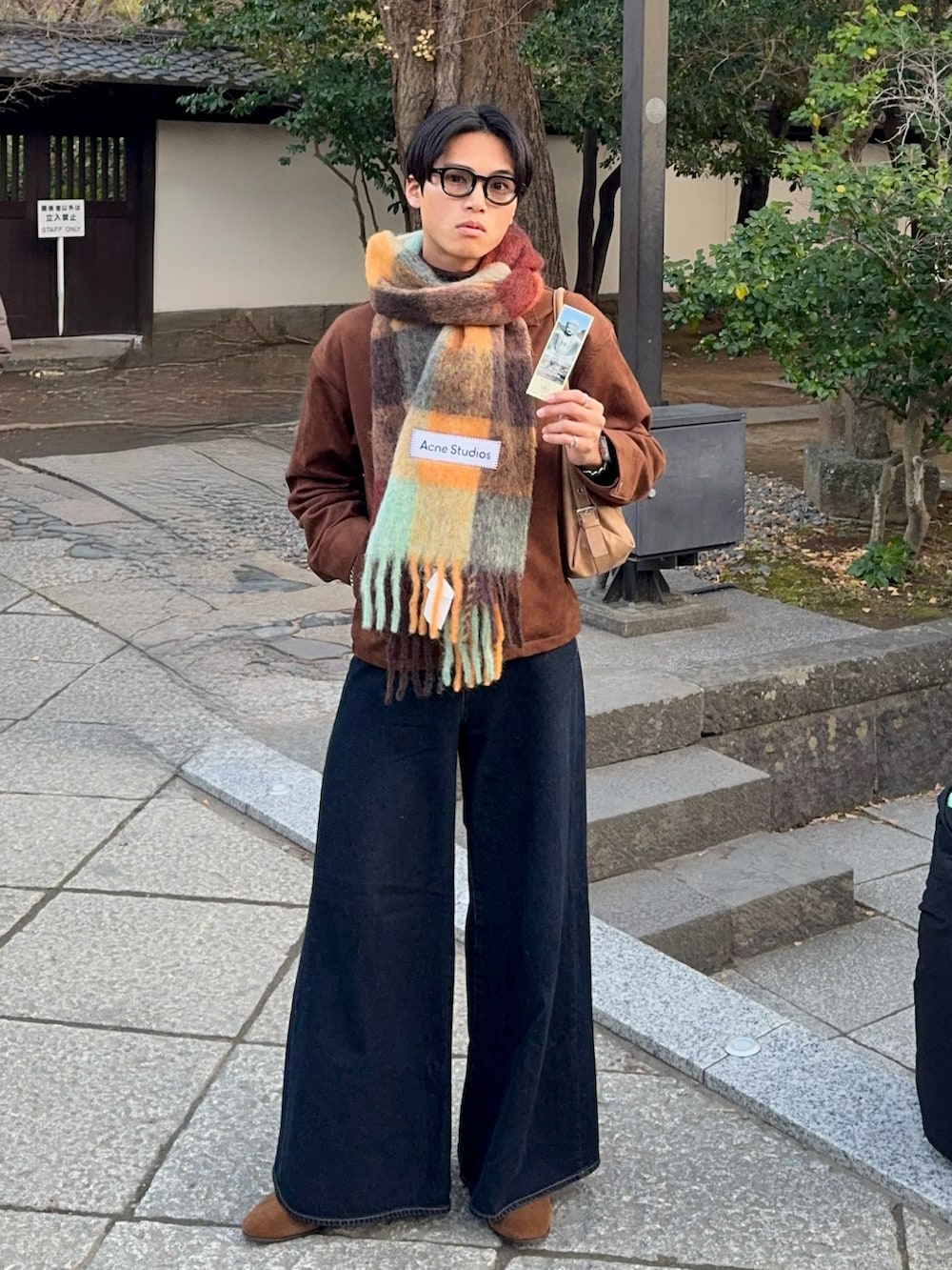 ブラウン系のブルゾン、ブルー系のデニムパンツ、ベージュ系のショルダーバッグを着用したメンズの冬コーディネートの3枚目の写真