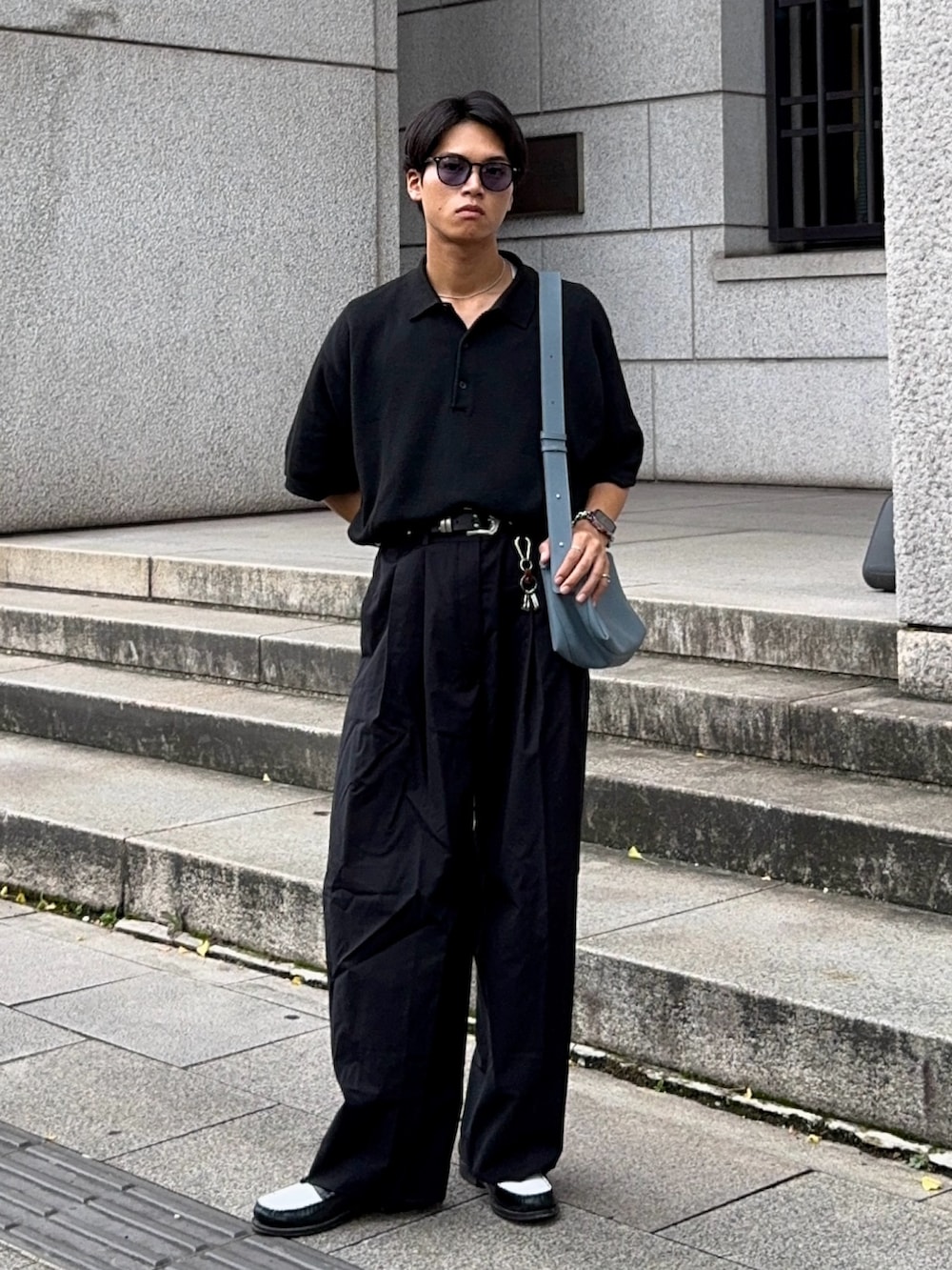 ブラック系のローファー、ブラック系のポロシャツ、ブルー系のショルダーバッグを着用したメンズの夏コーディネートの5枚目の写真