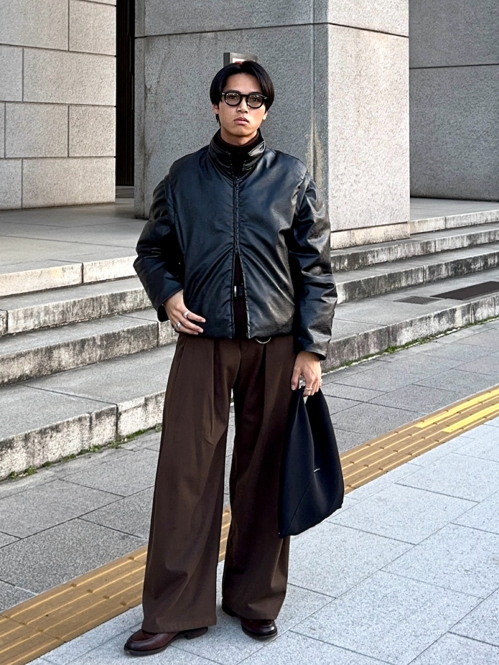 ブラック系のダウンジャケット/コート、ブラック系のハンドバッグ、ブラウン系のローファーを着用したメンズの冬コーディネートの3枚目の写真