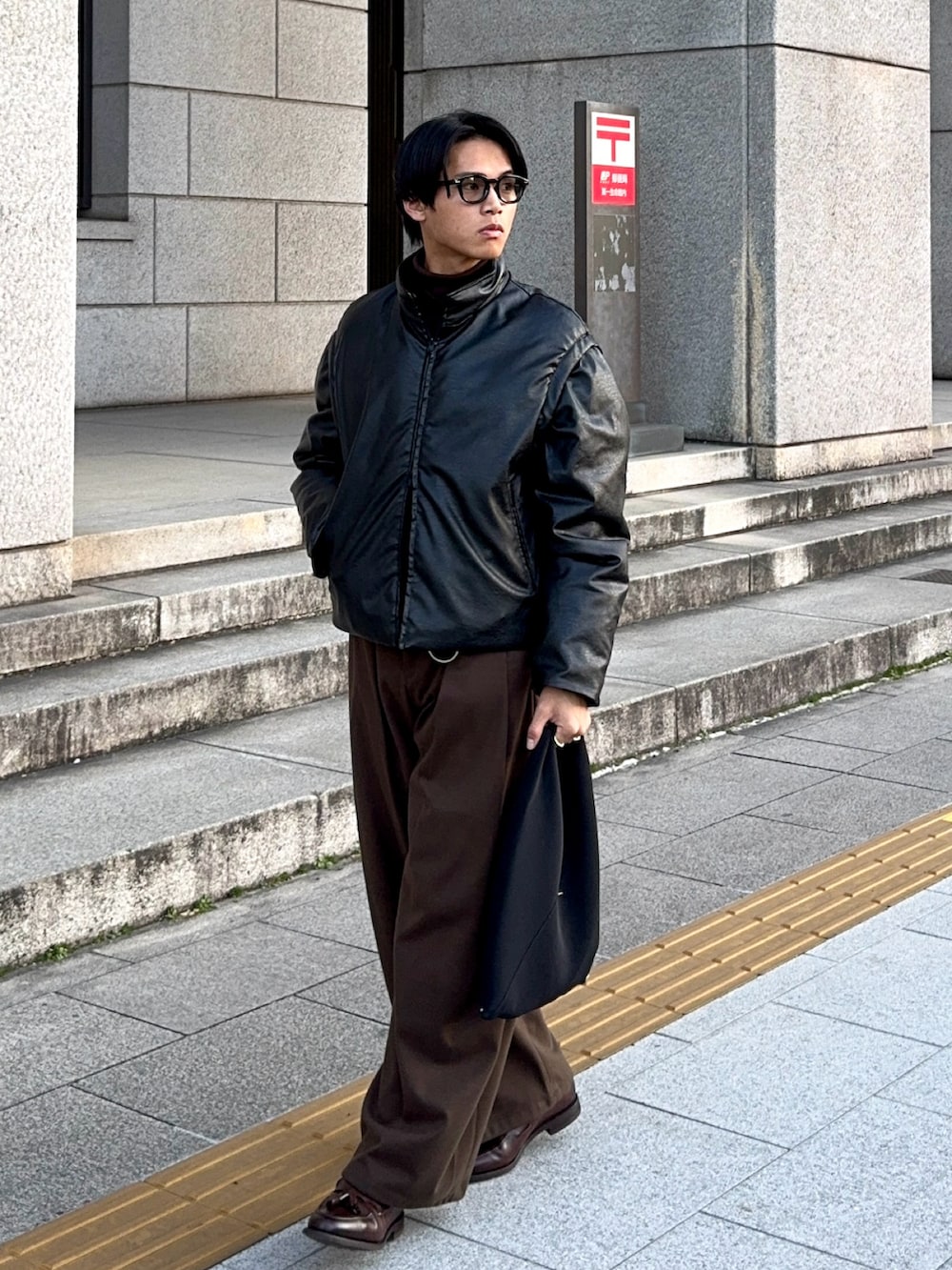 ブラック系のダウンジャケット/コート、ブラック系のハンドバッグ、ブラウン系のローファーを着用したメンズの冬コーディネートの5枚目の写真