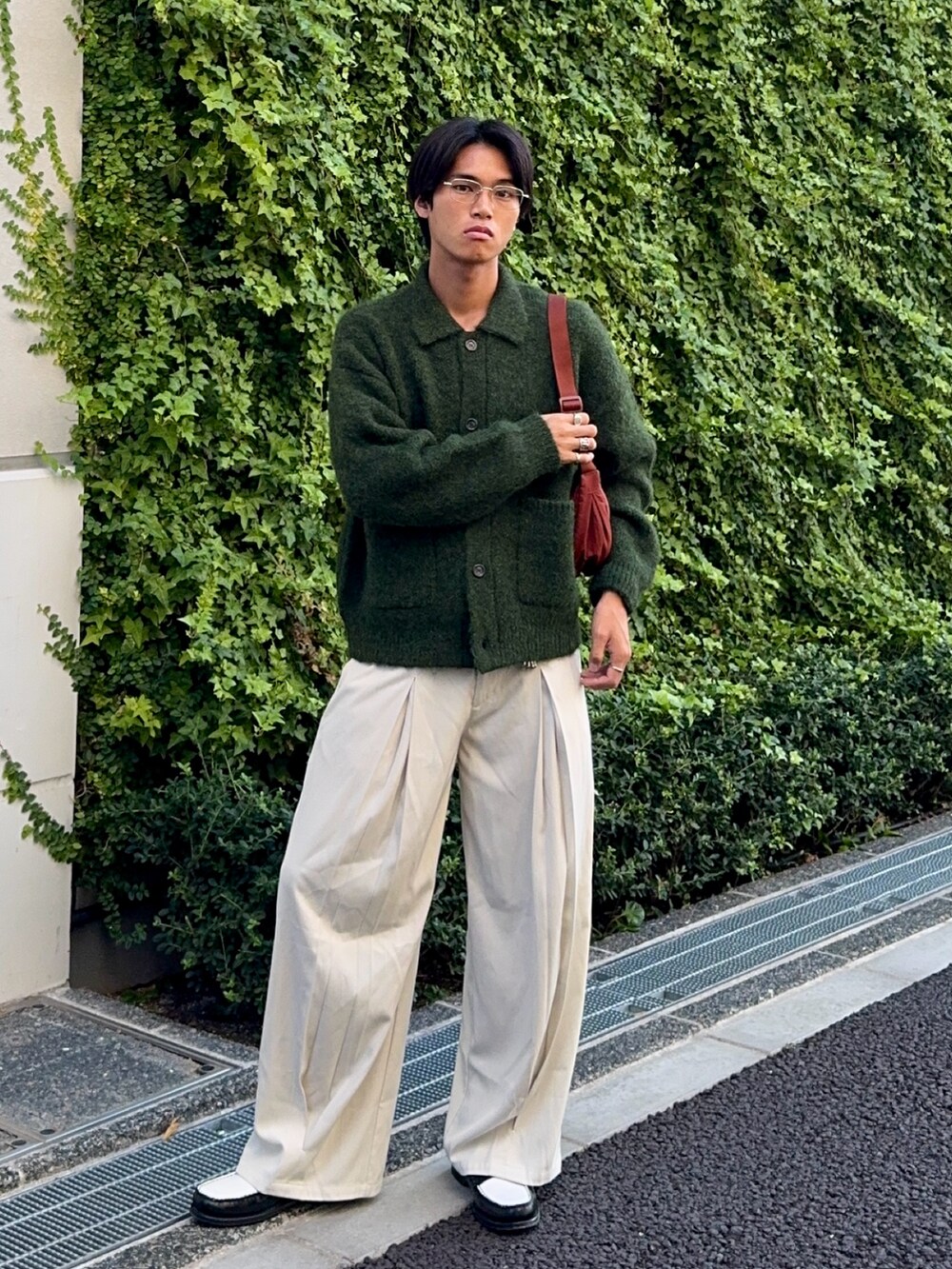 グリーン系のカーディガン/ボレロ、ブラック系のローファー、ホワイト系のスラックスを着用したメンズの秋コーディネートの5枚目の写真