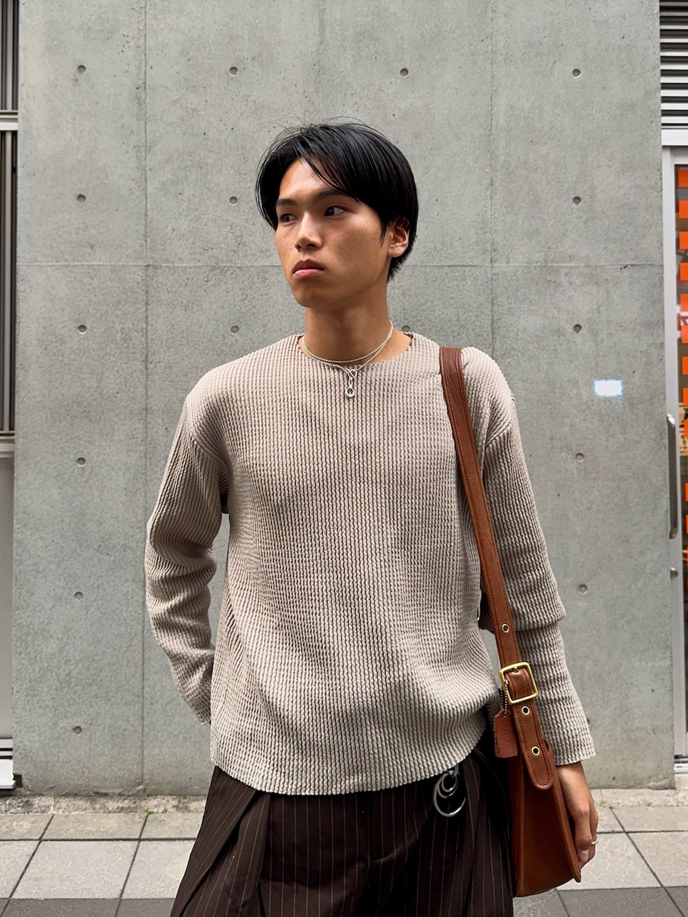 グリーン系のTシャツ/カットソー、ブラウン系のスラックス、ブラウン系のショルダーバッグを着用したメンズの夏コーディネートの2枚目の写真