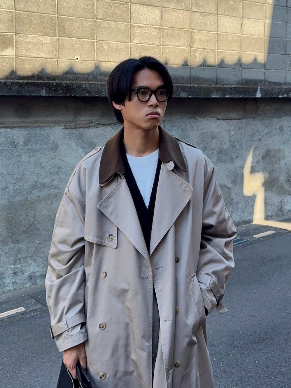 ブラック系のカーディガン/ボレロ、ベージュ系のトレンチコート、ベージュ系のスラックスを着用したメンズの冬コーディネートの2枚目の写真