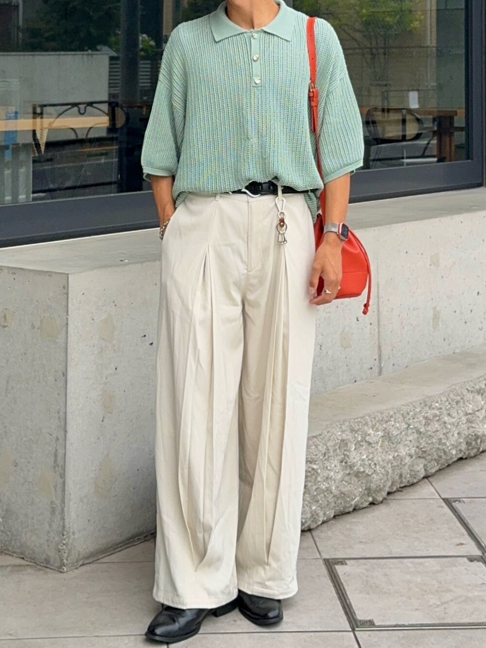 グリーン系のポロシャツ、オレンジ系のバッグ、ホワイト系のスラックスを着用したメンズの夏コーディネートの4枚目の写真
