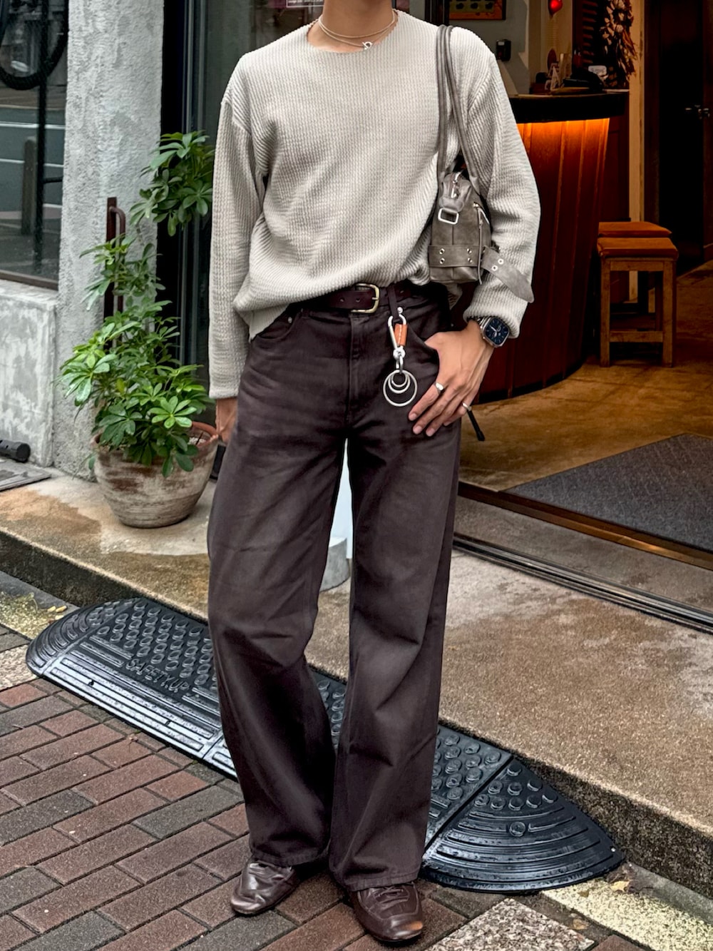 グリーン系のTシャツ/カットソー、ブラウン系のデニムパンツ、ブラウン系のショルダーバッグを着用したメンズの秋コーディネートの4枚目の写真
