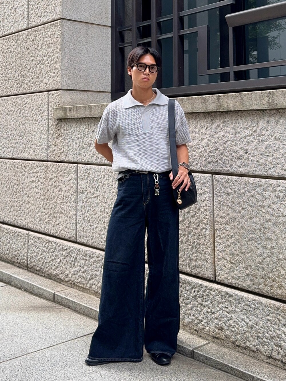 グレー系のポロシャツ、ブルー系のデニムパンツ、ブラック系のハンドバッグを着用したメンズの夏コーディネートの3枚目の写真