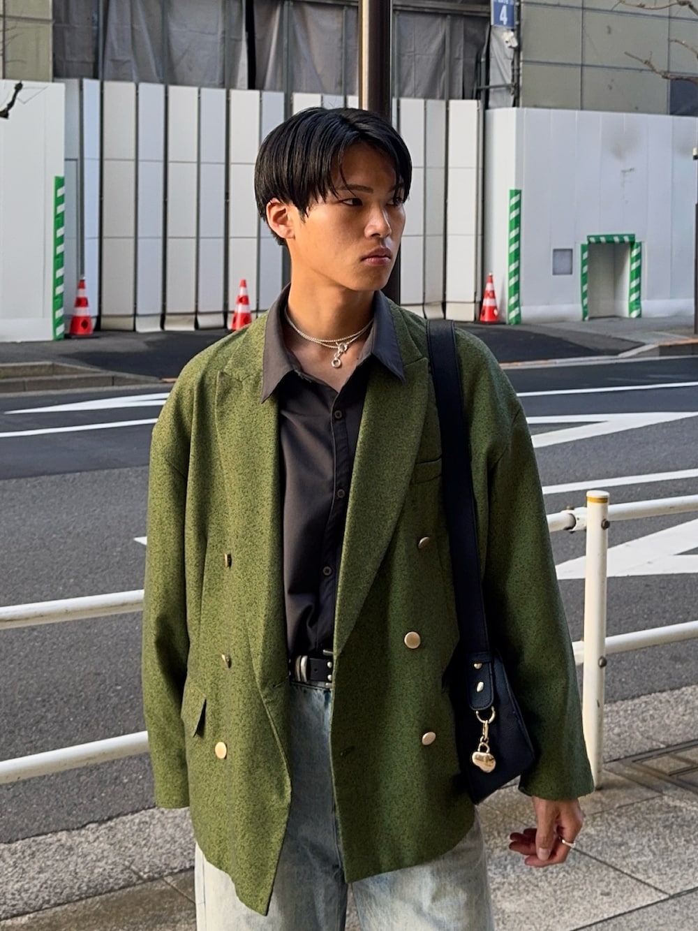 グリーン系のテーラードジャケット、ブラック系のハンドバッグ、ブラック系のローファーを着用したメンズの春コーディネートの2枚目の写真