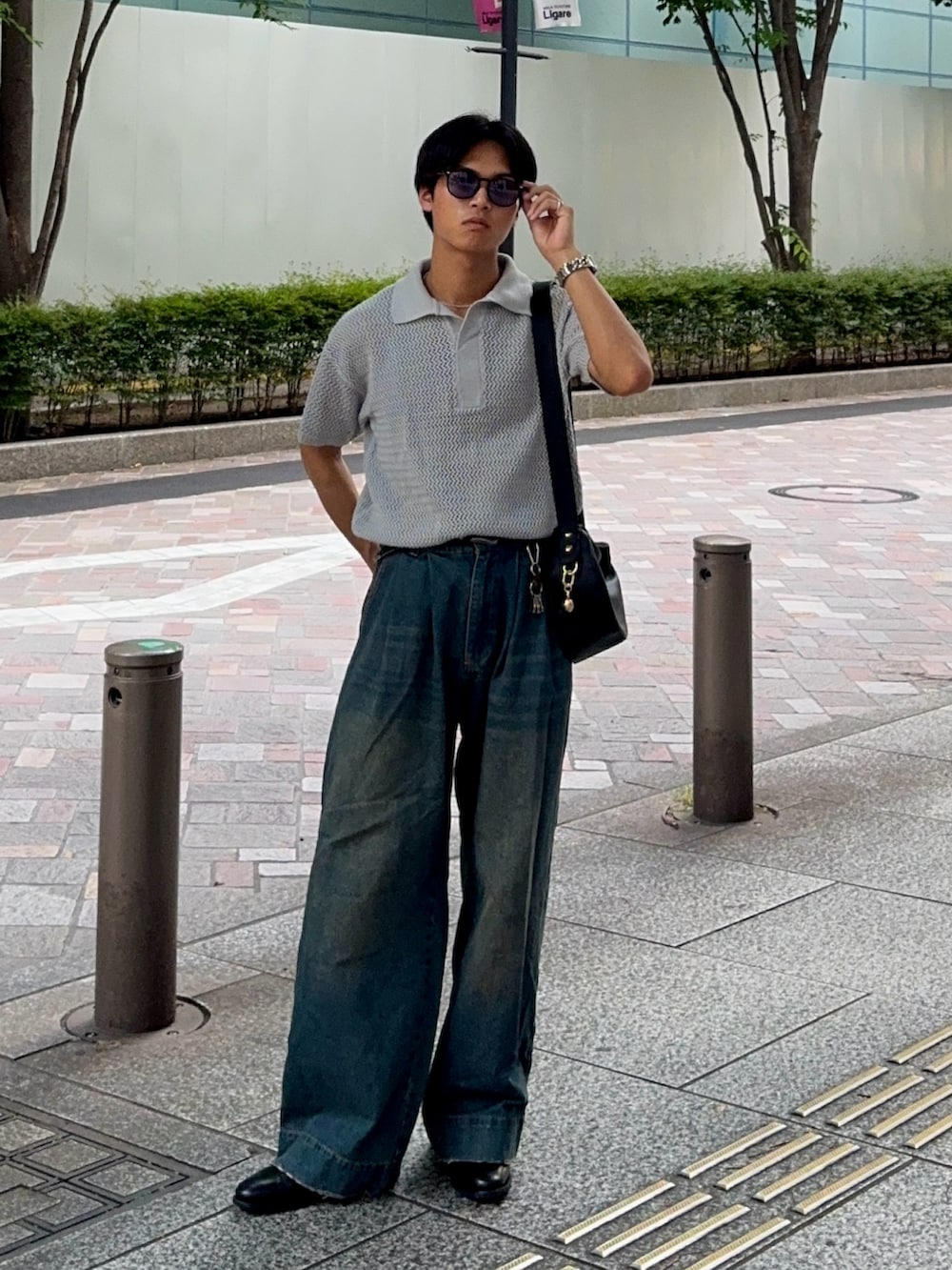 ブルー系のデニムパンツ、ブラック系のハンドバッグ、ブラック系のドレスシューズを着用したメンズの夏コーディネートの3枚目の写真