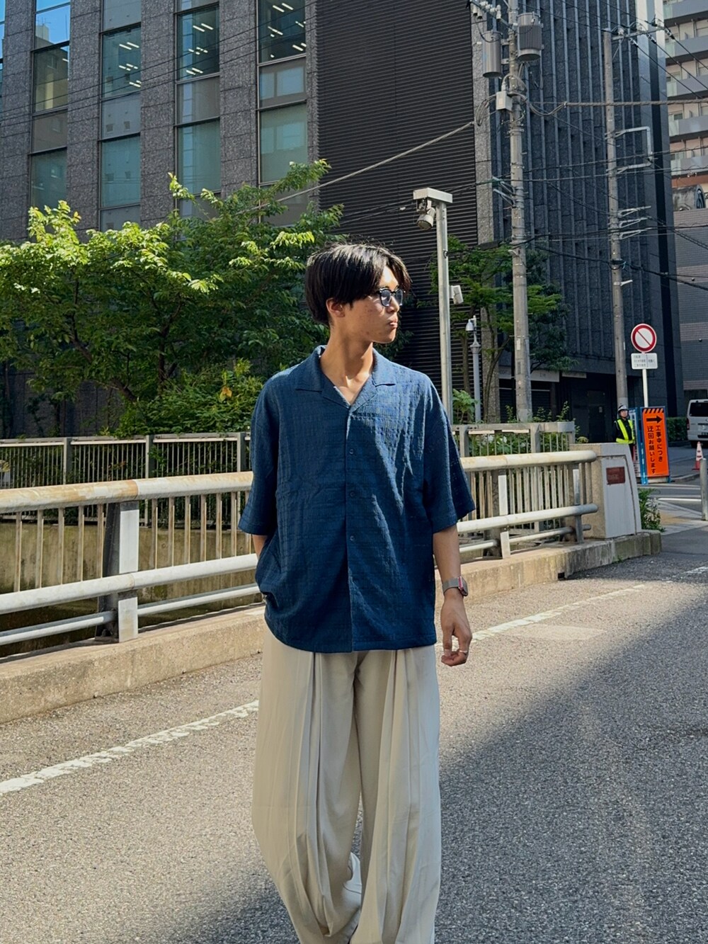 ブルー系のシャツ/ブラウス、ホワイト系のスラックス、ブラック系のハンドバッグを着用したメンズの春コーディネートの4枚目の写真