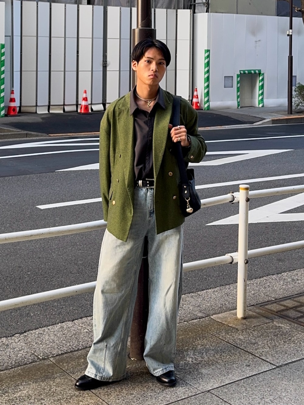 グリーン系のテーラードジャケット、ブラック系のハンドバッグ、ブラック系のローファーを着用したメンズの春コーディネートの5枚目の写真
