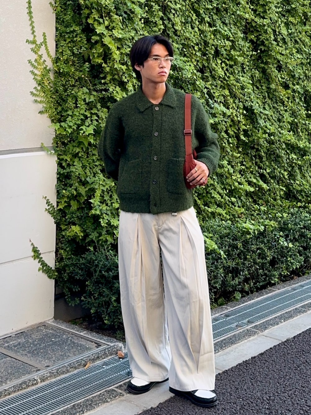 グリーン系のカーディガン/ボレロ、ブラック系のローファー、ホワイト系のスラックスを着用したメンズの秋コーディネートの3枚目の写真