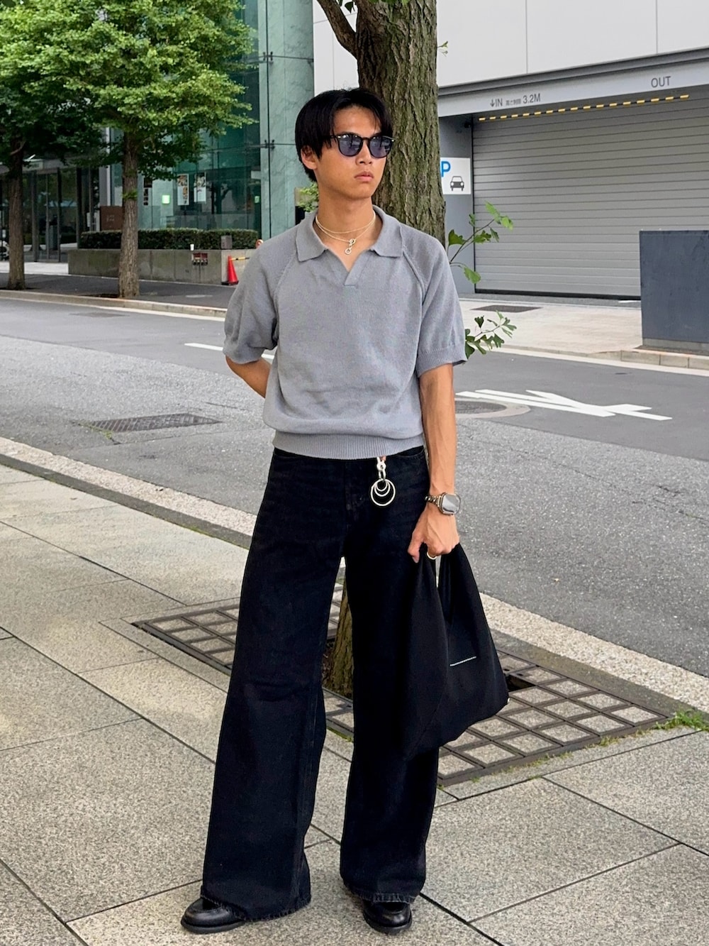 ブラック系のデニムパンツ、ブルー系のポロシャツ、ブラック系のハンドバッグを着用したメンズの夏コーディネートの5枚目の写真