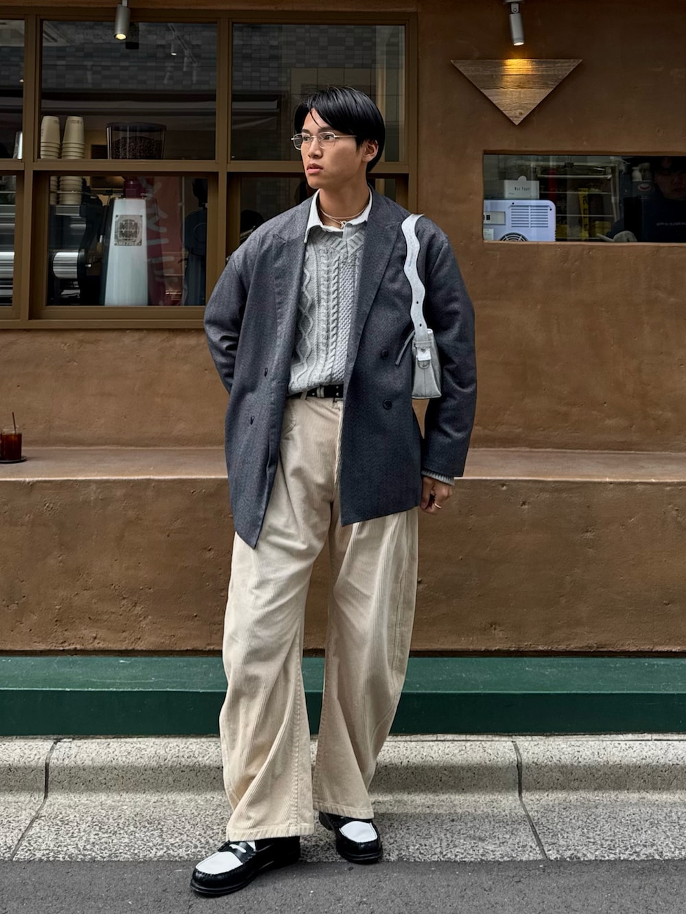 ベージュ系のスラックス、ブラック系のローファー、グレー系のテーラードジャケットを着用したメンズの春コーディネートの5枚目の写真