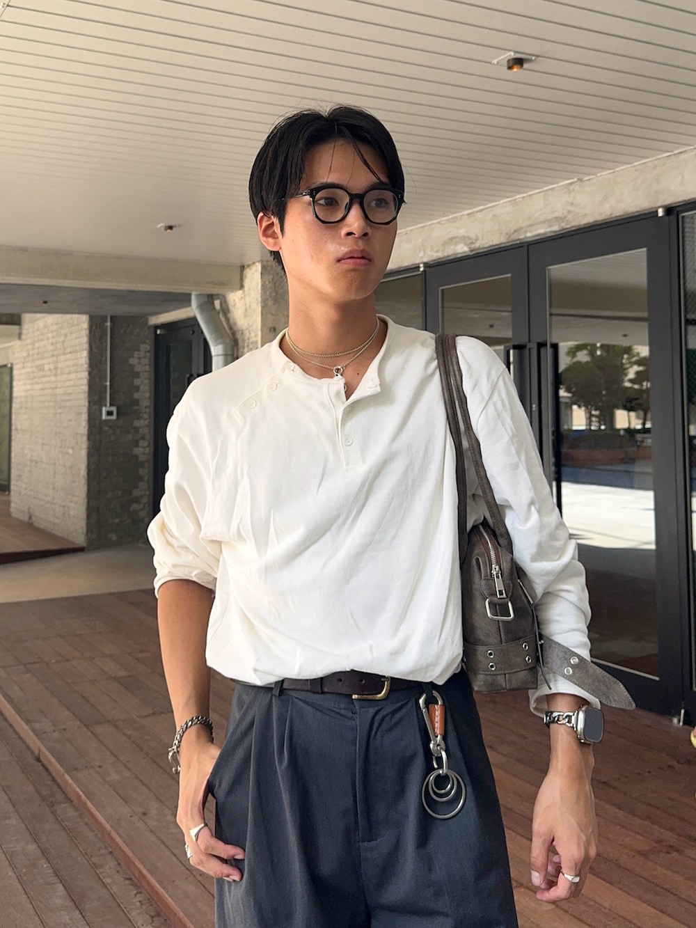 グレー系のスラックス、ホワイト系のTシャツ/カットソー、ブラウン系のショルダーバッグを着用したメンズの秋コーディネートの2枚目の写真