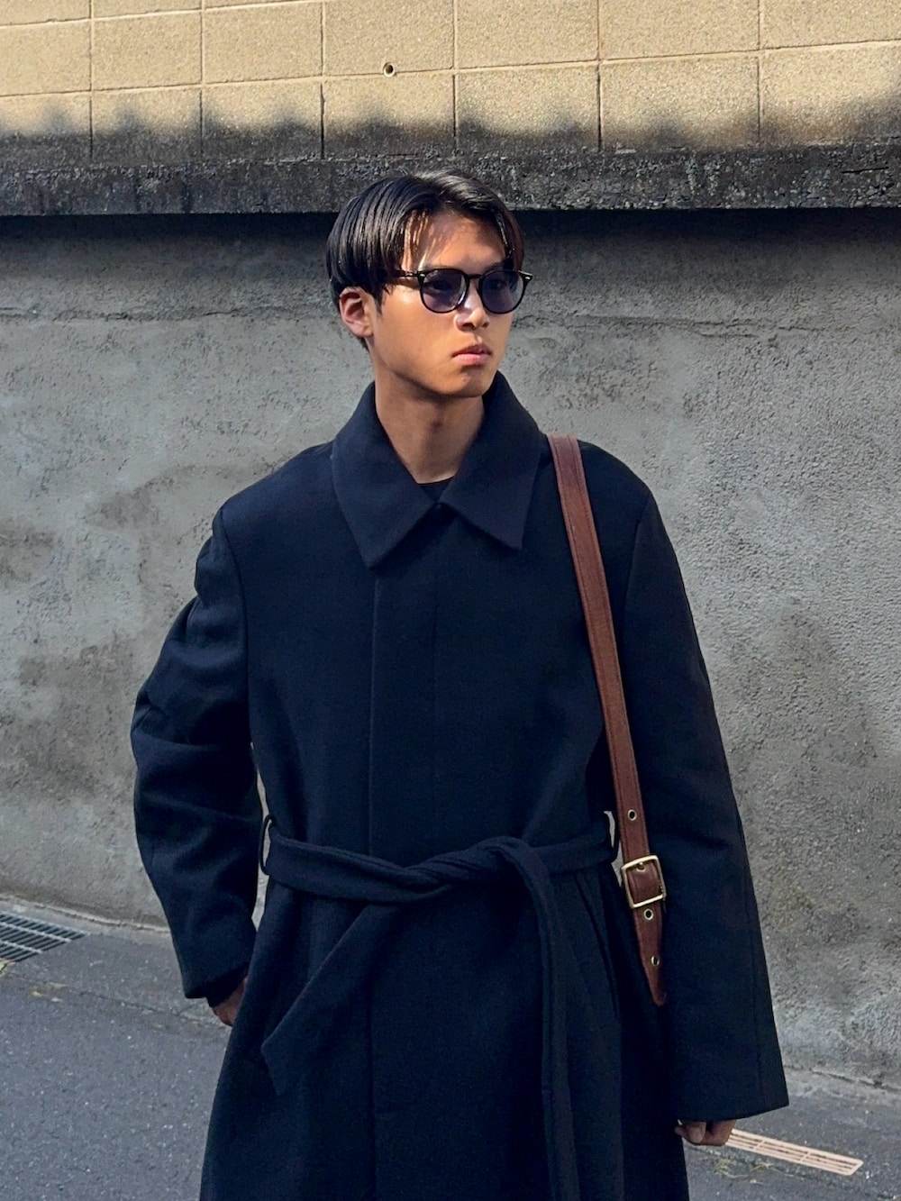 ブラック系のニット/セーター、ホワイト系のデニムパンツ、ブラウン系のローファーを着用したメンズの春コーディネートの2枚目の写真