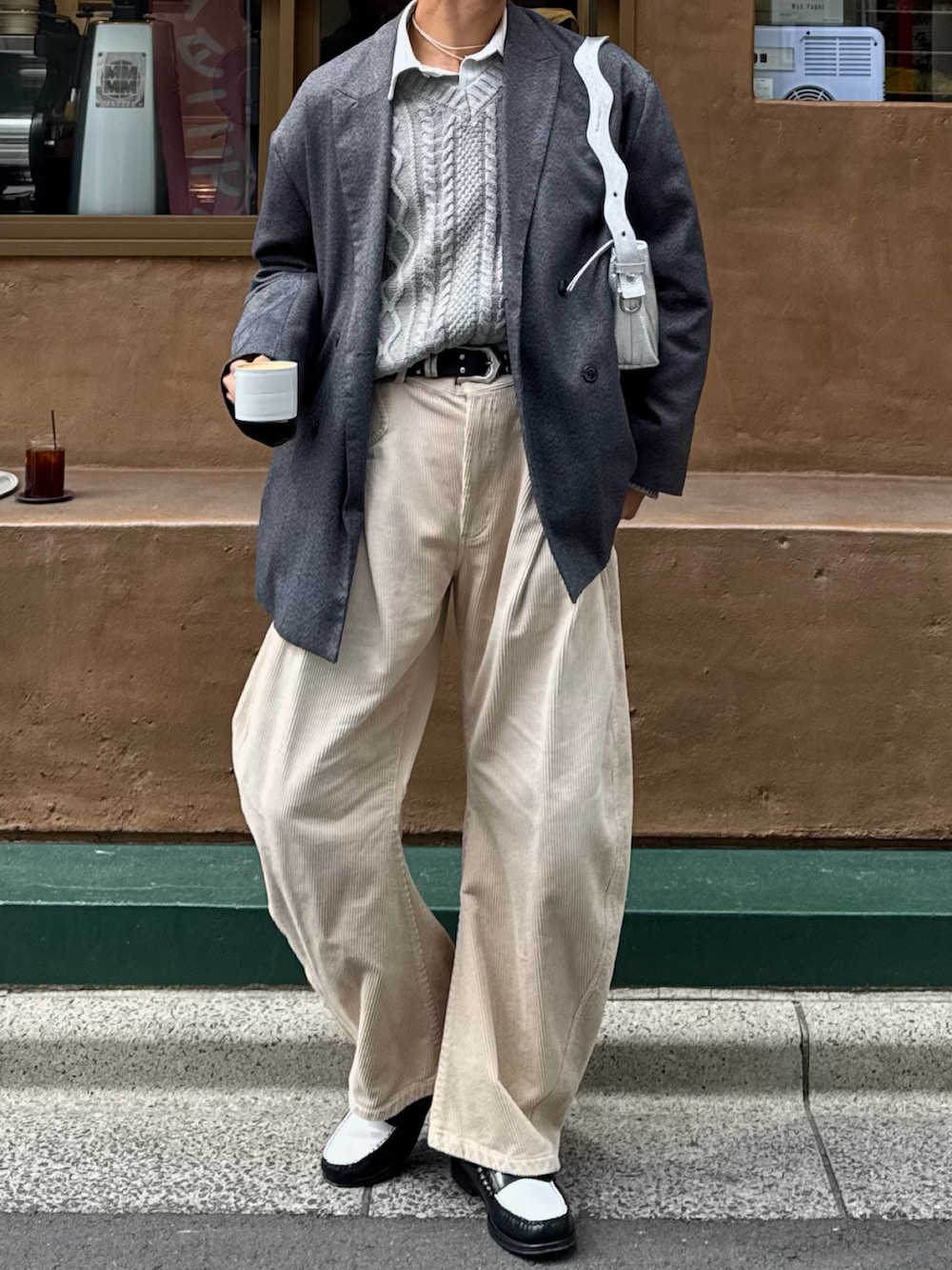 ベージュ系のスラックス、ブラック系のローファー、グレー系のテーラードジャケットを着用したメンズの春コーディネートの4枚目の写真