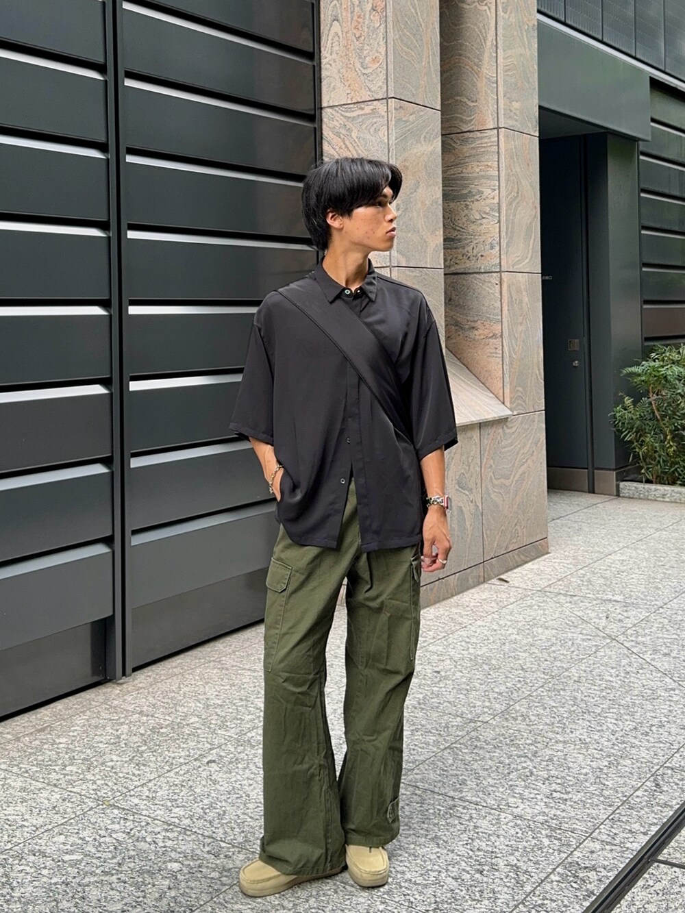 グリーン系のカーゴパンツ、ベージュ系のモカシン/デッキシューズ、ブラック系のシャツ/ブラウスを着用したメンズの夏コーディネートの5枚目の写真