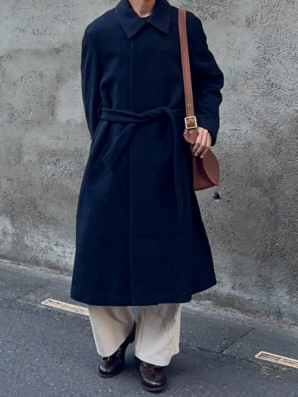 ブラック系のニット/セーター、ホワイト系のデニムパンツ、ブラウン系のローファーを着用したメンズの春コーディネートの4枚目の写真