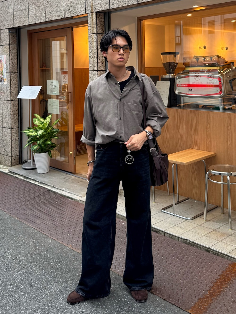 ブラック系のタンクトップ、ブラック系のデニムパンツ、ブラウン系のショルダーバッグを着用したメンズの秋コーディネートの5枚目の写真