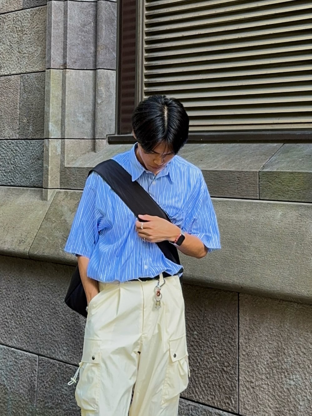 ブルー系のシャツ/ブラウス、ブラック系のショルダーバッグ、ホワイト系のカーゴパンツを着用したメンズの夏コーディネートの2枚目の写真