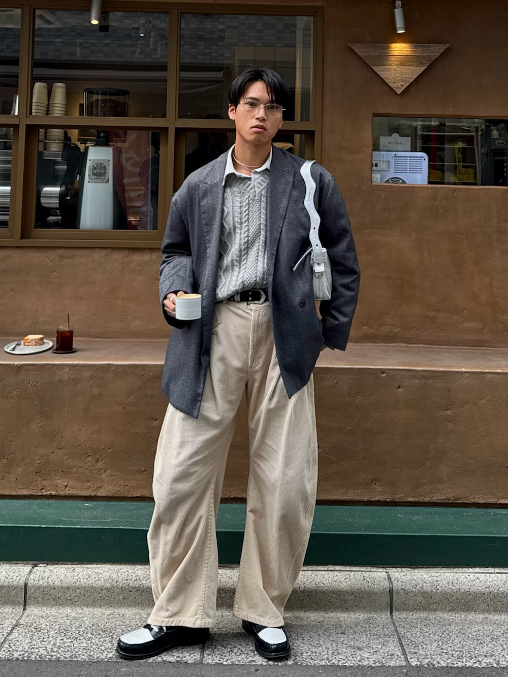 ベージュ系のスラックス、ブラック系のローファー、グレー系のテーラードジャケットを着用したメンズの春コーディネートの3枚目の写真