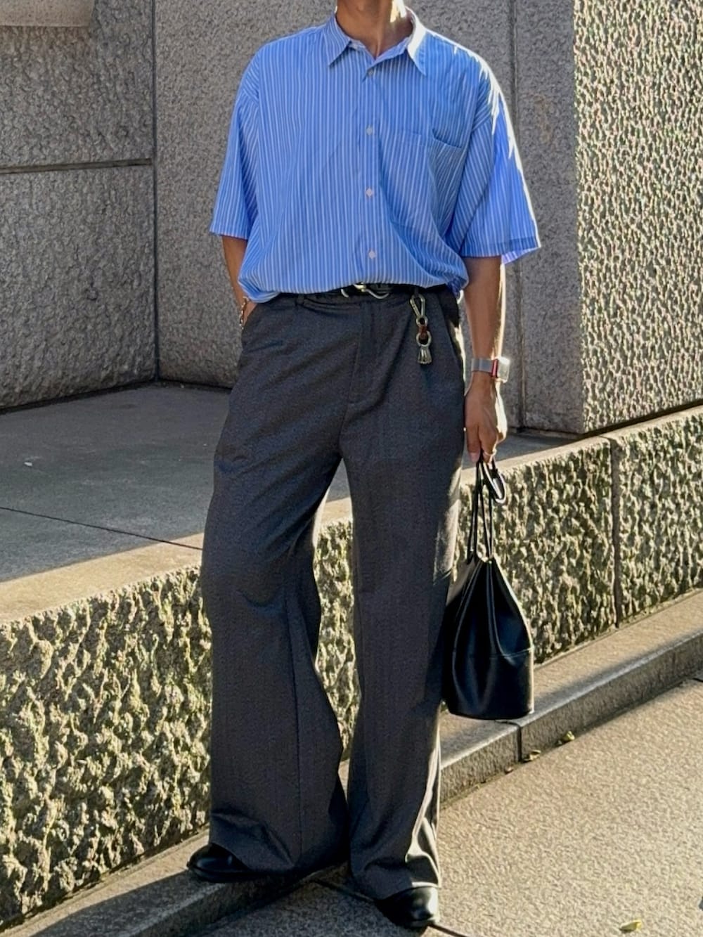 グレー系のスラックス、ブラック系のバッグ、ブルー系のシャツ/ブラウスを着用したメンズの夏コーディネートの4枚目の写真