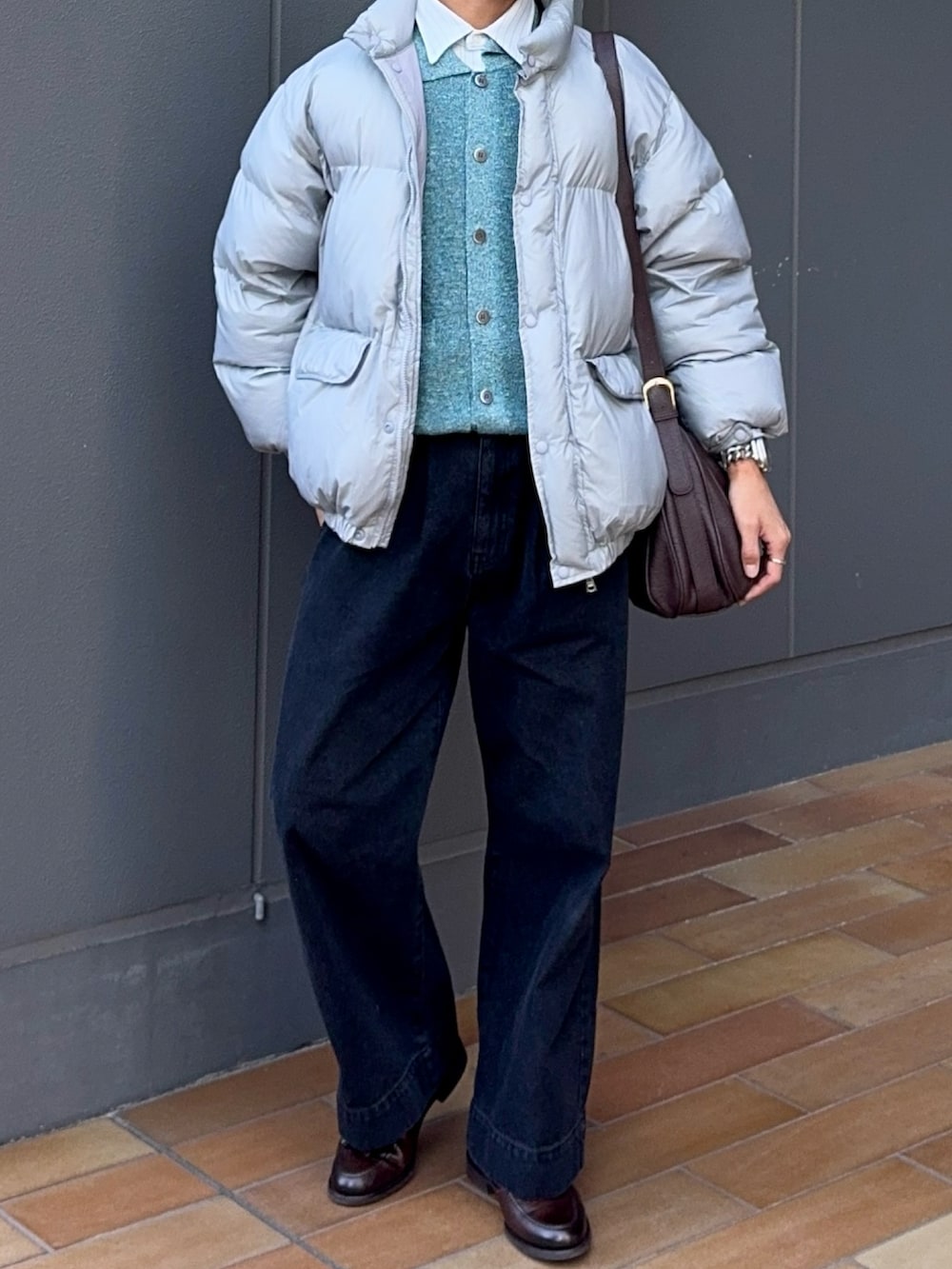 ブラック系のデニムパンツ、ブラウン系のローファー、グレー系のダウンジャケット/コートを着用したメンズの冬コーディネートの4枚目の写真