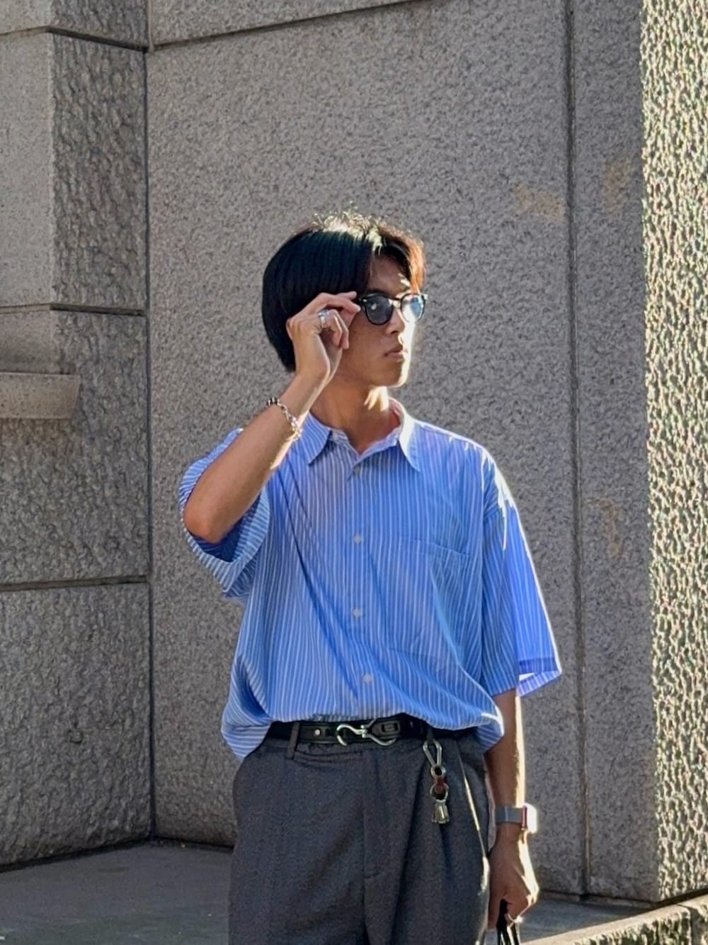 グレー系のスラックス、ブラック系のバッグ、ブルー系のシャツ/ブラウスを着用したメンズの夏コーディネートの2枚目の写真