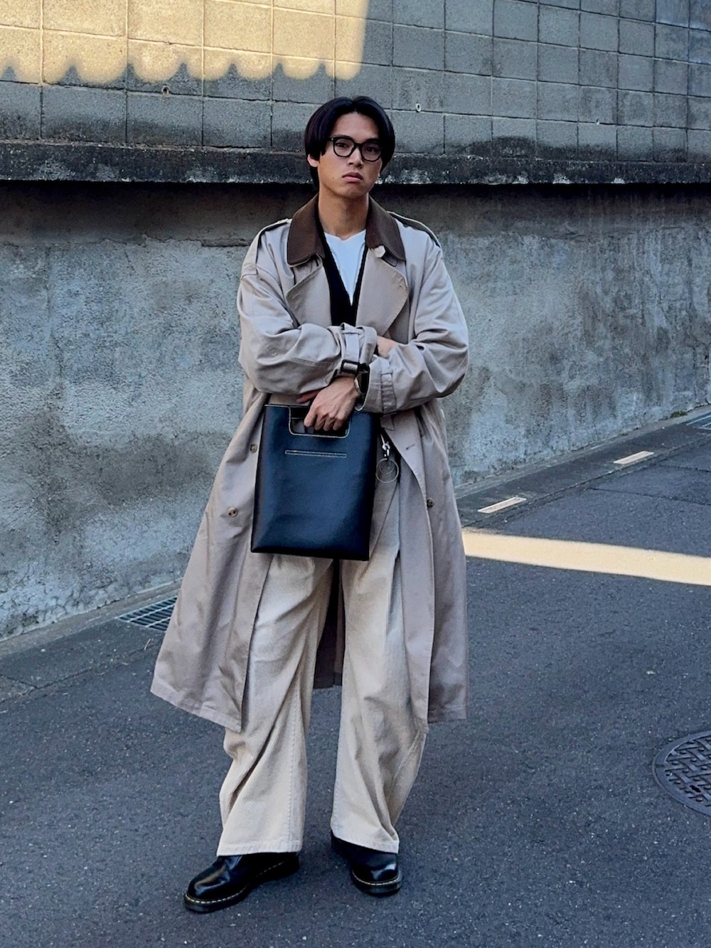 ブラック系のカーディガン/ボレロ、ベージュ系のトレンチコート、ベージュ系のスラックスを着用したメンズの冬コーディネートの3枚目の写真