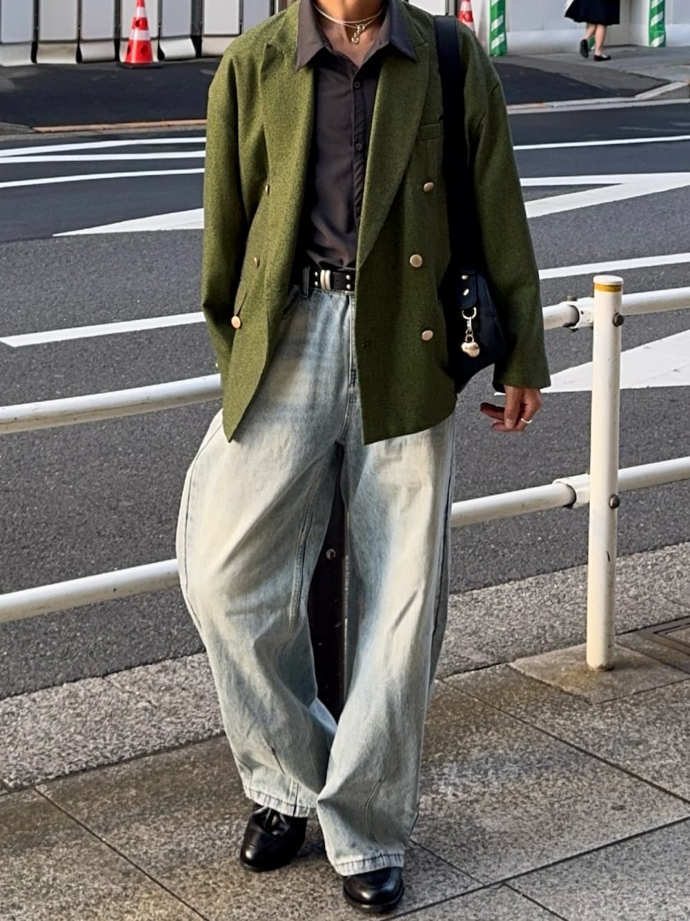 グリーン系のテーラードジャケット、ブラック系のハンドバッグ、ブラック系のローファーを着用したメンズの春コーディネートの4枚目の写真