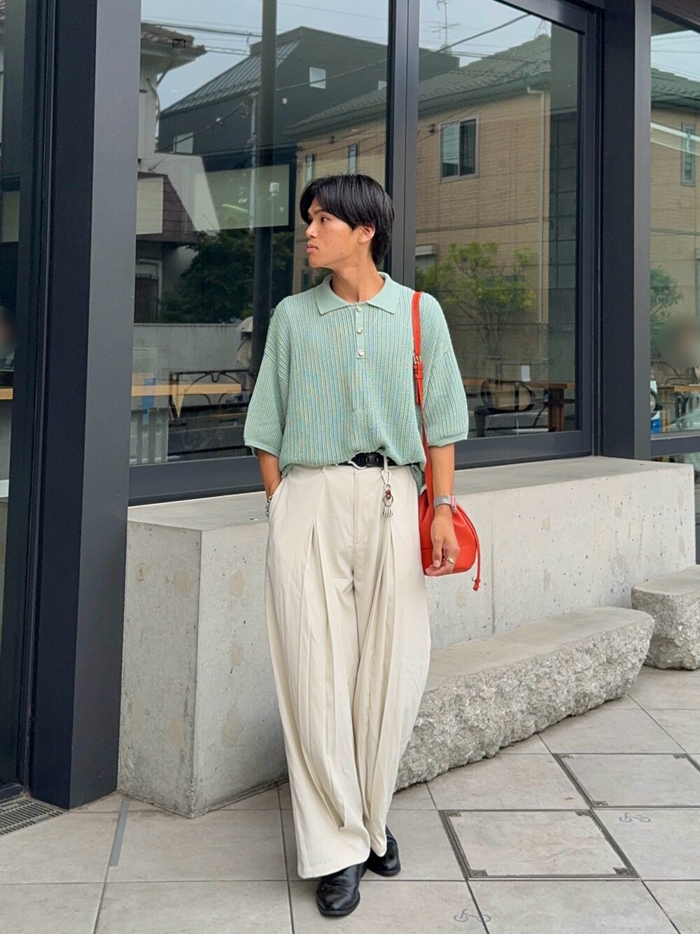 グリーン系のポロシャツ、オレンジ系のバッグ、ホワイト系のスラックスを着用したメンズの夏コーディネートの5枚目の写真