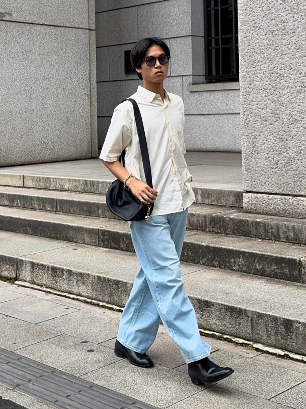 ブラック系のハンドバッグ、ベージュ系のシャツ/ブラウス、ブルー系のデニムパンツを着用したメンズの夏コーディネートの3枚目の写真