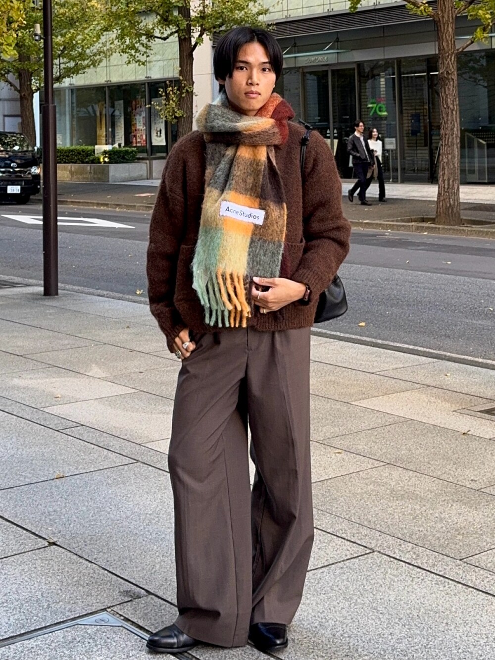 ブラウン系のスラックス、ブラック系のドレスシューズ、ブラウン系のカーディガン/ボレロを着用したメンズの冬コーディネートの5枚目の写真