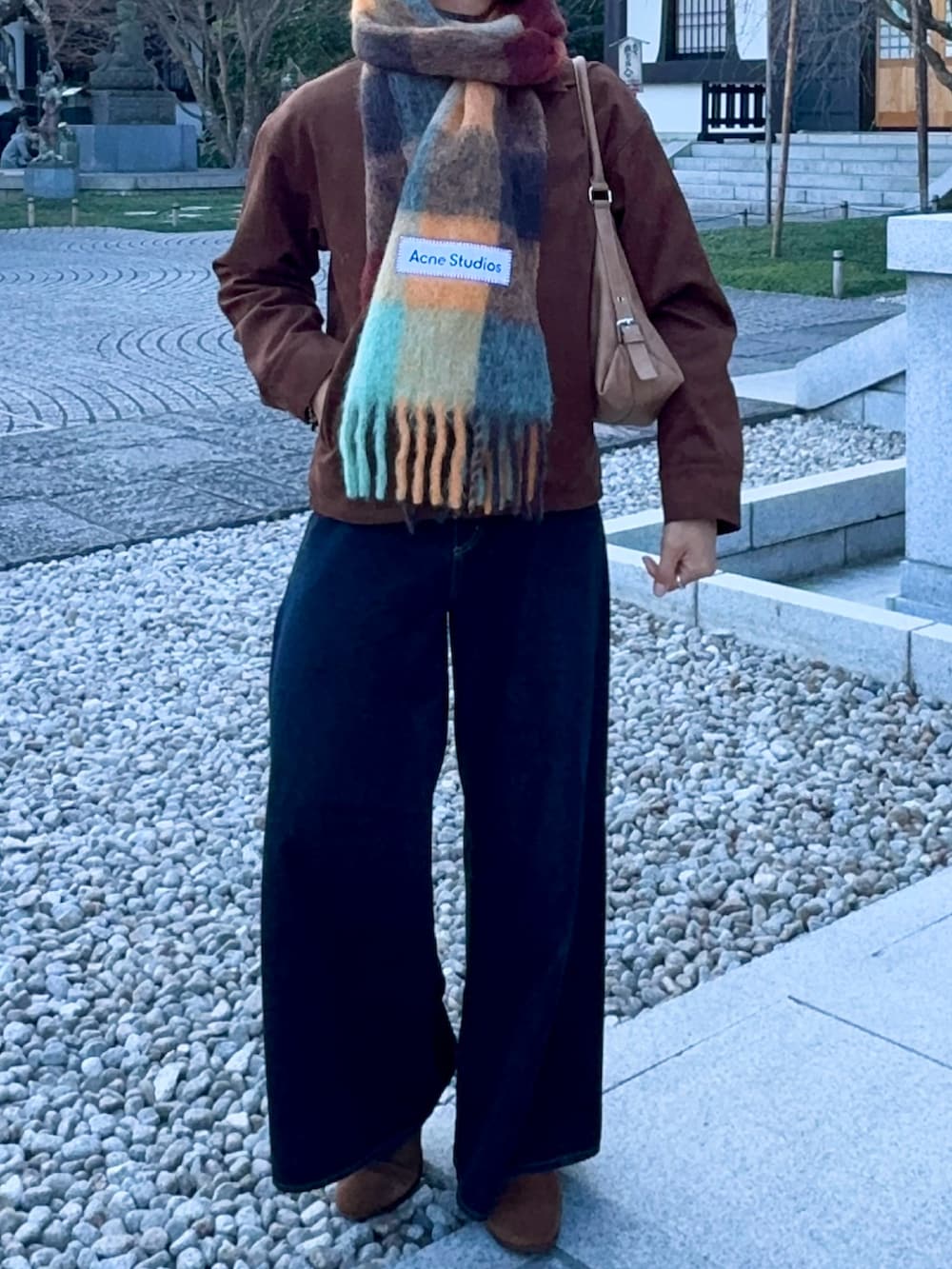 ブラウン系のブルゾン、ブルー系のデニムパンツ、ベージュ系のショルダーバッグを着用したメンズの冬コーディネートの4枚目の写真