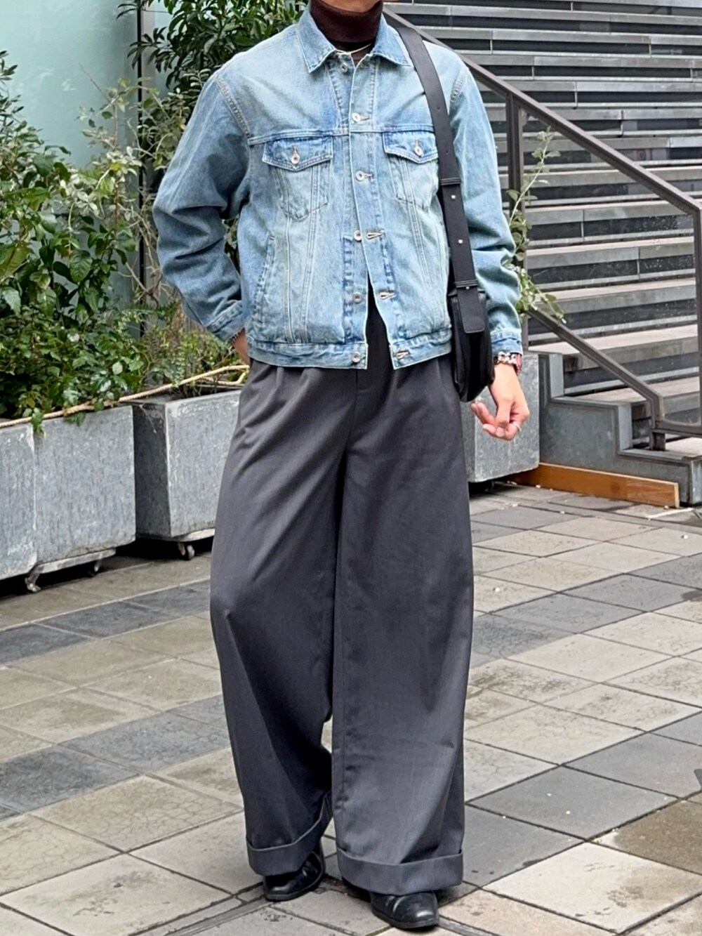 ブルー系のデニムジャケット、グレー系のスラックス、ブラック系のショルダーバッグを着用したメンズの冬コーディネートの4枚目の写真