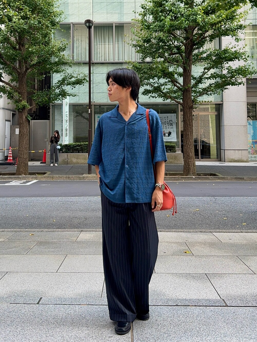 ブルー系のシャツ/ブラウス、オレンジ系のバッグ、ブラック系のスラックスを着用したメンズの夏コーディネートの5枚目の写真