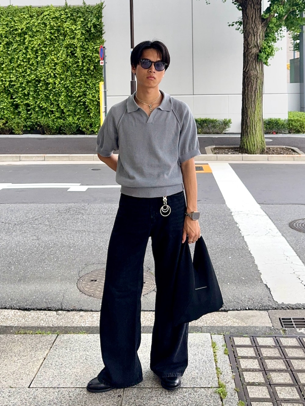 ブラック系のデニムパンツ、ブルー系のポロシャツ、ブラック系のハンドバッグを着用したメンズの夏コーディネートの3枚目の写真