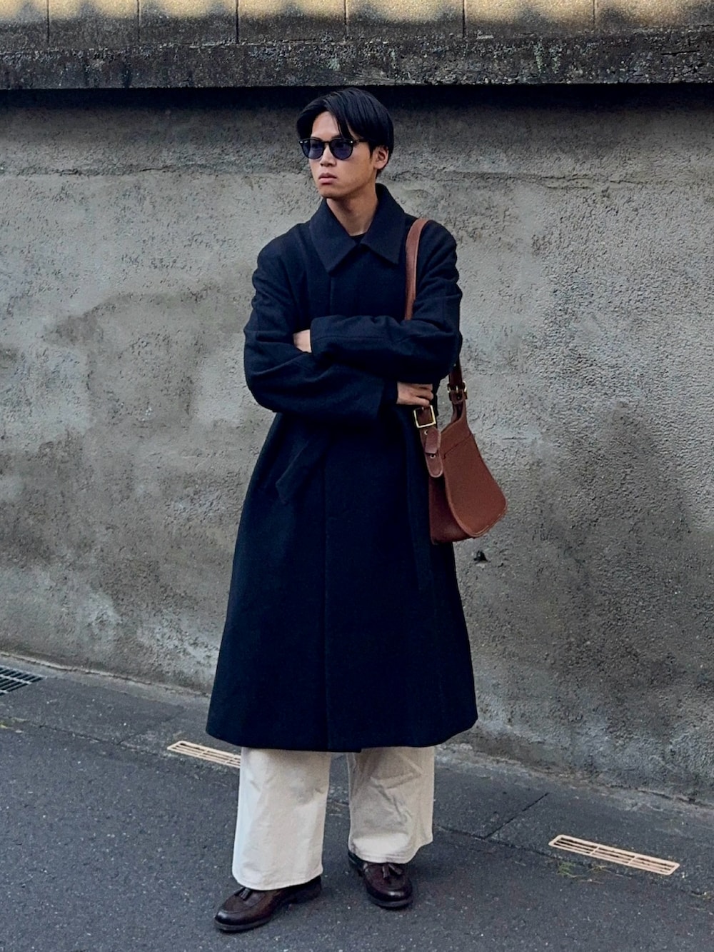 ブラック系のニット/セーター、ホワイト系のデニムパンツ、ブラウン系のローファーを着用したメンズの春コーディネートの3枚目の写真